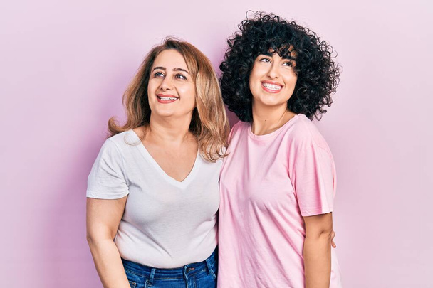 Middle east mother and daughter wearing casual clothes looking away to side with smile on face, natural expression. laughing confident.  - Photo, Image