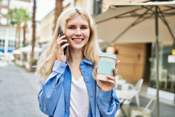 Junge blonde Frau an einem sonnigen Tag im Freien telefoniert - Foto, Bild