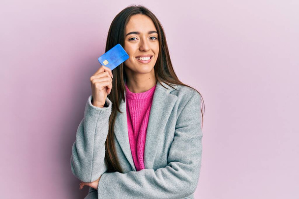 Jovencita hispana sosteniendo tarjeta de crédito sonriendo con una sonrisa alegre y fresca en la cara. mostrando dientes.  - Foto, imagen