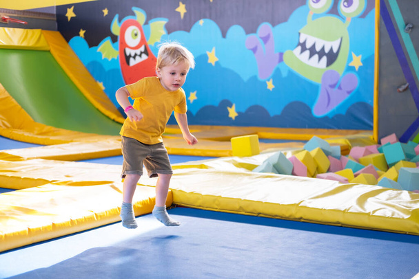 cute blond little boy jumps in a trampoline park, children activity - Valokuva, kuva