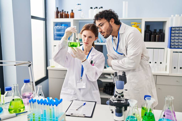 Homem e mulher cientistas parceiros olhando tubo de ensaio em laboratório - Foto, Imagem