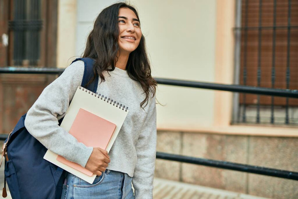 Молода студентка Близького Сходу посміхається щасливий тримає книгу в місті
. - Фото, зображення