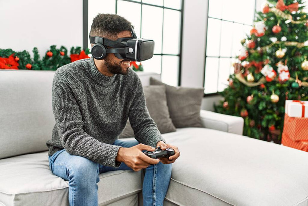 Νέοι Αφροαμερικανοί γιορτάζουν τα Χριστούγεννα παίζοντας βιντεοπαιχνίδι εικονικής πραγματικότητας στο σπίτι. - Φωτογραφία, εικόνα