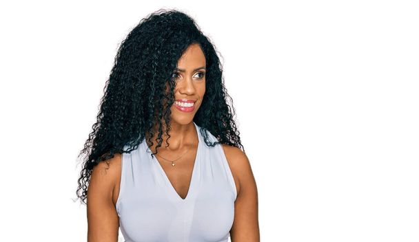 Mulher afro-americana de meia-idade vestindo estilo casual com camisa sem mangas olhando para o lado com sorriso no rosto, expressão natural. rindo confiante.  - Foto, Imagem