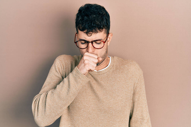 Young hispanic man wearing casual clothes and glasses feeling unwell and coughing as symptom for cold or bronchitis. health care concept.  - Photo, Image