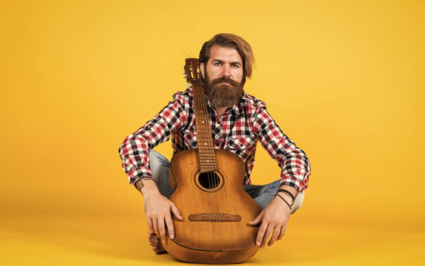 acoustic band. cheerful handsome mature man playing guitar and smiling while sitting on yellow background. Portrait of happy bearded male playing guitar. a lonely musician - Foto, Imagem