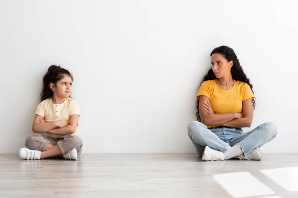 Äiti-tytär konflikteja. Loukkaantunut pieni tyttö ja äiti istuu erillään lattialla - Valokuva, kuva