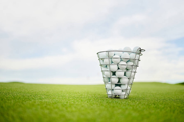 Basket with golf balls on a green golf course - 写真・画像
