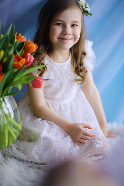 Hermosa chica en vestidos blancos con un magnífico ramo de primeros tulipanes. Día Internacional de la Mujer. Chica con tulipanes. - Foto, imagen