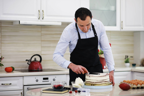 机の前にマスターペストリーシェフ。家庭でデザートを作る。お菓子作りに従事するアルメニア人. - 写真・画像