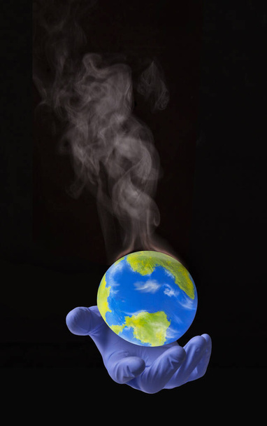 Surgycal glove doctor hand hold a warming smoke planet earth globe. - Foto, Imagen