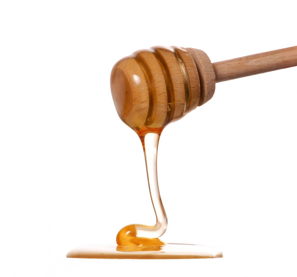 Wood honey dipper straining honey on white background. - Zdjęcie, obraz
