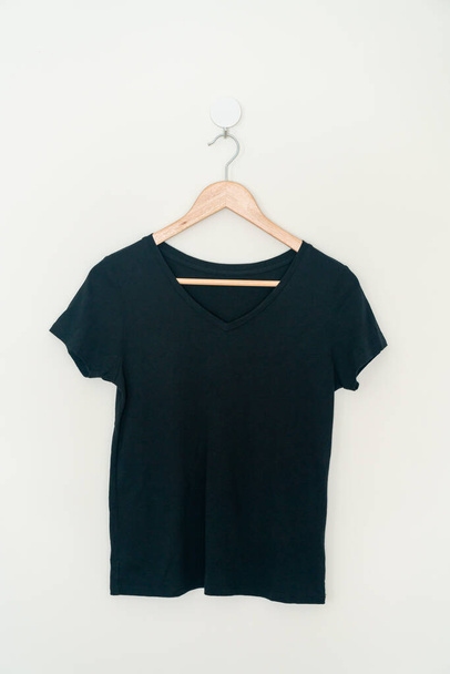woman t-shirt hanging with wood hanger on wall - Фото, изображение