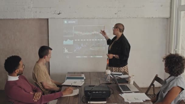 Μέτριο μήκος Καυκάσου γυναίκα διευθυντής φορώντας γυαλιά κάνει παρουσίαση στους ειδικούς του οικονομικού τμήματος, χρησιμοποιώντας γράφημα με δεδομένα, συναδέλφους που έχουν συνάντηση στην αίθουσα συνεδριάσεων - Πλάνα, βίντεο