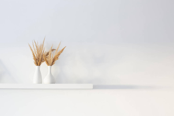 bouquet of dried wild flowers in white vase on wooden shelf on background white wall - Foto, immagini