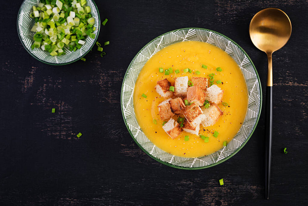 Creamy pumpkin puree soup with croutons, peppers and green onions. Top view, above - Photo, Image