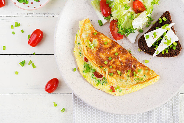 Breakfast. Omelette with tomatoes, cheese, green onions and sandwich with feta cheese.  Frittata - italian omelet. Top view, above - Foto, afbeelding