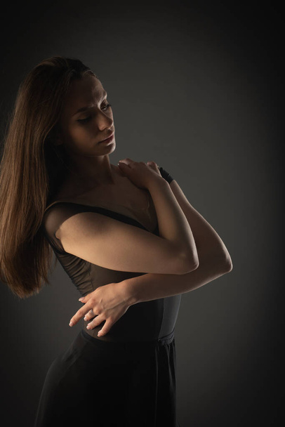 Portrait of elegant ballerina girl hugging herself on grey background - Фото, изображение
