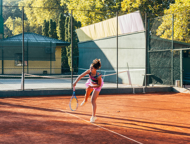 A young female tennis player serving on a clay court - Photo, Image
