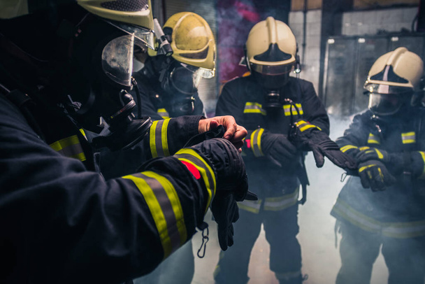 Palomiehet univormussa käsineet ja kaasunaamarit palolaitoksen sisällä
 - Valokuva, kuva