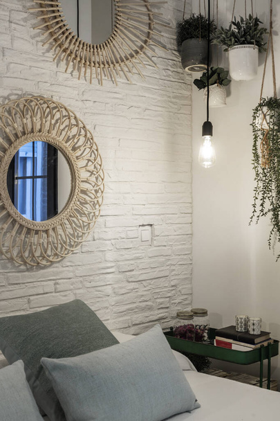 Γωνία ενός υπνοδωματίου με λευκό τοίχο από τούβλα, κρεμαστά φυτά και μαξιλάρια στο κεφαλάρι - Φωτογραφία, εικόνα