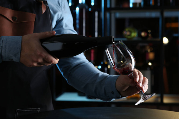 Bartender pouring red wine from bottle into glass indoors, closeup - Φωτογραφία, εικόνα
