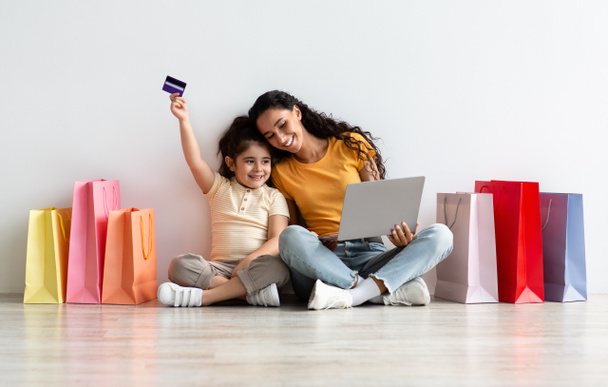 Маленька дівчинка і мама робить онлайн покупки з ноутбуком і кредитною карткою
 - Фото, зображення