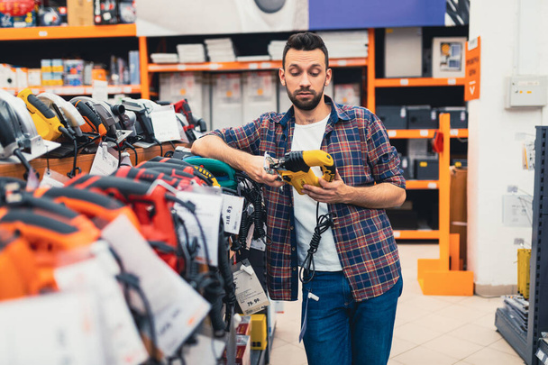 client masculin choisit un scie sauteuse dans un magasin d'outils électriques - Photo, image
