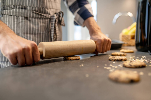 Hands of man pressing rolling pin on raw cookie - 写真・画像