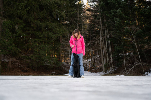 犬従順トレーナー作業とともに彼女のラブラドール取得犬スタンディングで彼女の足の間に外で冬の性質. - 写真・画像