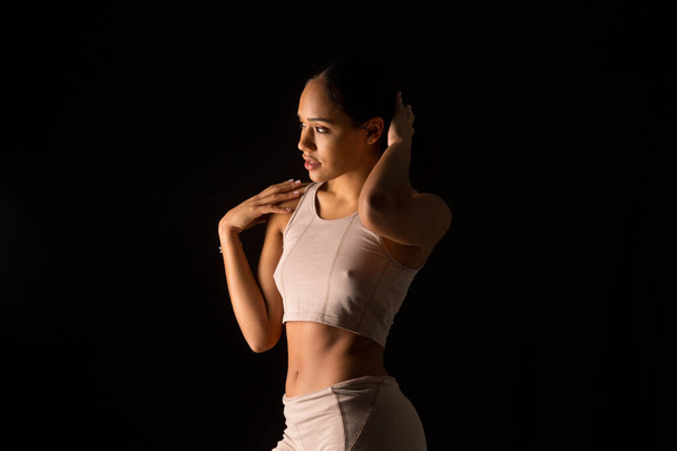 Intimes Foto einer Frau in Sportkleidung auf schwarzem Hintergrund - Foto, Bild