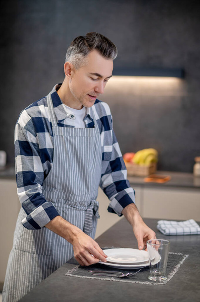 Man serving table neatly with clean tableware - Photo, image