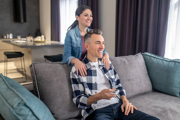 Woman touching shoulders of man sitting on couch - Foto, immagini