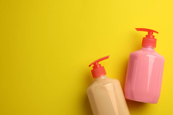 Bottles of liquid soap on yellow background, flat lay. Space for text - Фото, зображення