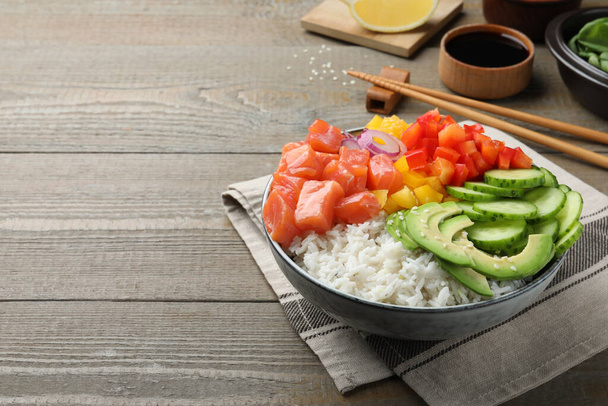 Delicious poke bowl with salmon and vegetables served on wooden table. Space for text - Fotografie, Obrázek