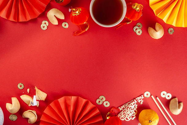 Chińskie tło nowego roku. Czerwony i złoty żółty płaskowyż z tradycyjnym chińskim noworocznym wystrojem, koperty z życzeniami, złote monety, wentylatory, chińskie latarnie, pomarańcze i herbata - Zdjęcie, obraz