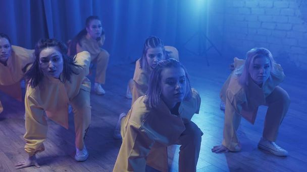 Un gruppo di belle ragazze che ballano in una stanza con illuminazione blu in abiti gialli. Danze - Foto, immagini