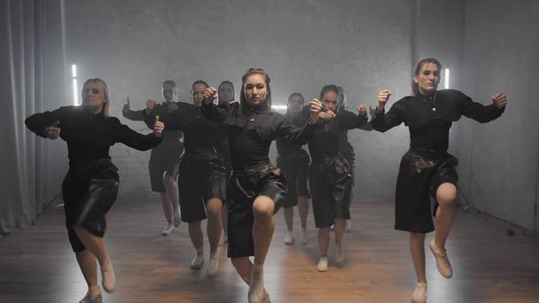 A group of beautiful girls dancing indoors in black suits. Dances - Photo, image