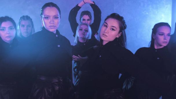 A group of beautiful girls dancing in a room with blue lighting in black suits. Dances - Foto, immagini