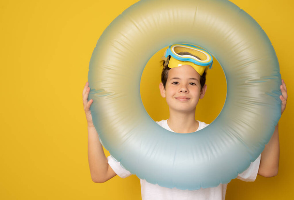 Cute boy with inflatable ring and diving goggles on yellow background - Photo, Image