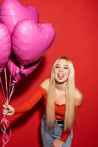 Beautiful smiling girl with balloons on a red background. Valentines day for all lovers. - Fotografie, Obrázek