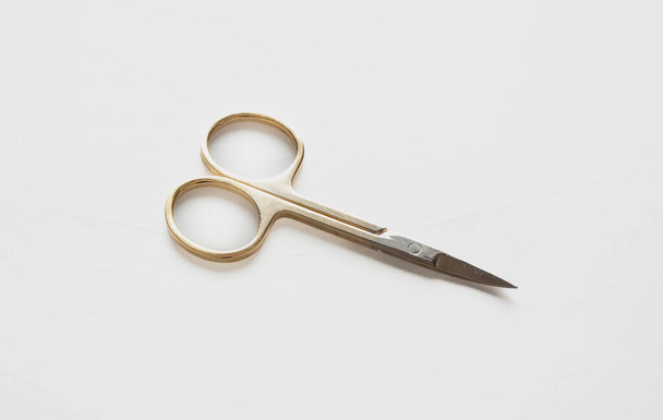 Small scissors. Steel nail scissors, gold hundle isolated on white background, design element. - 写真・画像