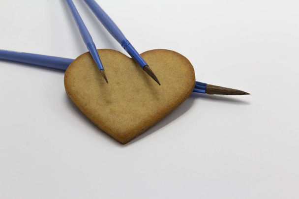 biscuits en forme de coeur sur fond blanc avec pinceaux bleus, décoration alimentaire, Art pâtissier, décoration de biscuits, horizontal, espace de copie - Photo, image