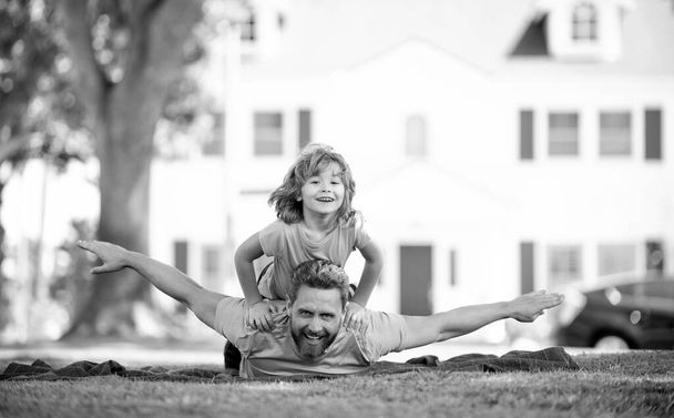 Uçuyormuş gibi yap. Baba ve oğul battaniyeye uzanarak eğleniyorlar. Aile eğlencesi günü. Yaz tatili - Fotoğraf, Görsel