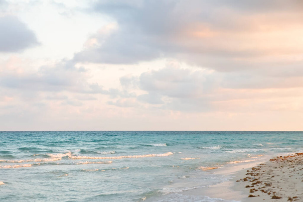 Ευγενική ανατολή στην ακτή του Ατλαντικού Ωκεανού. Θαλασσινό τοπίο με γαλαζοπράσινα κύματα της θάλασσας και ροζ ανταύγειες σε ένα σκηνικό σε τουριστική παραλία. Χαλαρωτικές διακοπές δίπλα στη θάλασσα στο μαγευτικό ηλιοβασίλεμα του Βαραδερού - Φωτογραφία, εικόνα