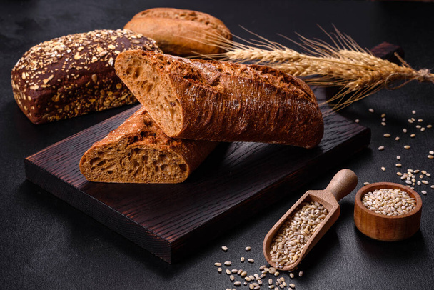 Fresh Bread on black background, top view, copy space. Homemade fresh baked various loafs of wheat and rye bread - 写真・画像