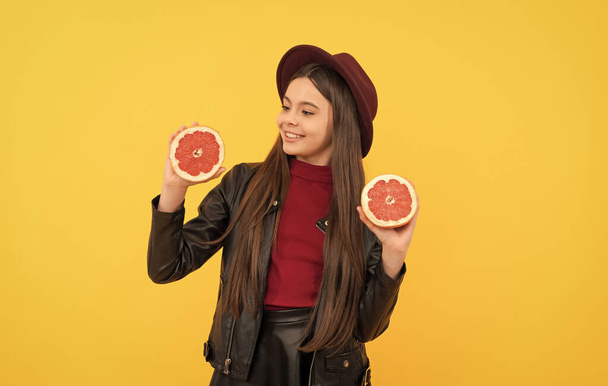 happy teen girl in hat and leather jacket hold cut grapefruit, vitamin - Fotografie, Obrázek