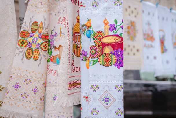 Traditional Ukrainian embroidered towels, called rushnyk, and tablecloths for Easter celebration at market stall. Ukrainian traditions. Selective focus - Foto, Imagem
