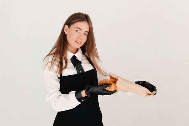 Camarera empacando croissants en bolsa de papel en la cafetería, sirviendo a sus clientes durante coronavirus - Foto, Imagen