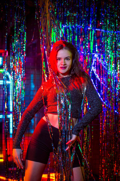 Studio Portrait of a young fashion woman dancing. Style. High fashion girl model in stylish clothes in colorful neon lights portrait. Sexy woman in trendy dress under pink and purple light at studio. - Фото, зображення